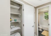 Thumbnail 22 of 27 - a bathroom with a white door and a white toilet next to a white shelf with white towels